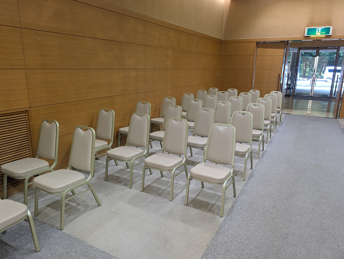 白石葬祭が案内する野田市の斎場小ホールに整列したベージュの式場用椅子と出入口
